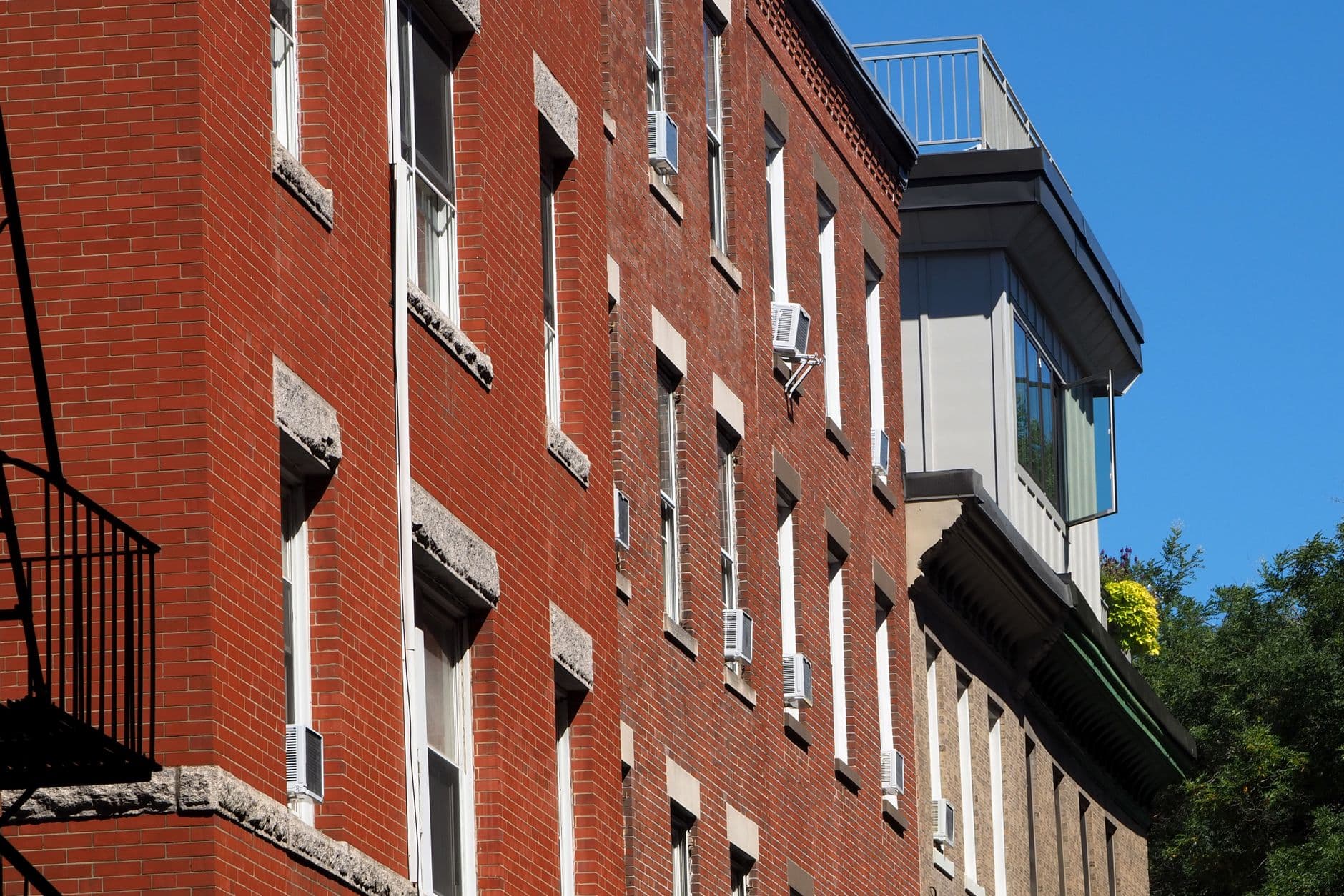 Red brick historic building facade with fire escape in Boston, showcasing urban architecture.
