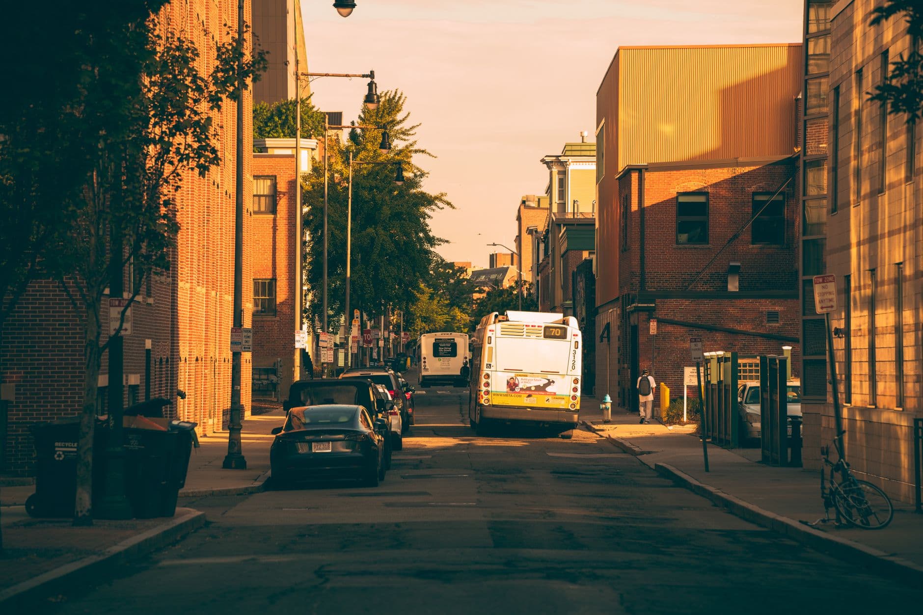 Vibrant city street view with a bus and cars under warm sunset lighting in Boston.